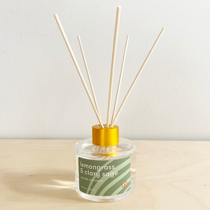 Aroma diffuser with lemongrass and clary sage scent, featuring wooden reeds in a clear glass bottle with a yellow cap.