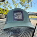 Green cap with a 'HOSS' logo on a wooden surface outdoors