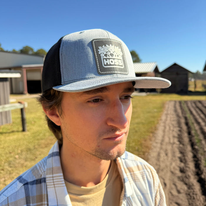 Man wearing a cap with a Hoss logo on a farm